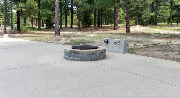 Accessible campground site with paved surface, raised fire ring, and accessible utility hookups