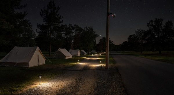 Campground at night with pathway lighting and security camera monitoring an empty road