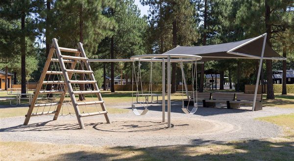 Modern campground playground with sensor-equipped equipment and shaded seating nearby