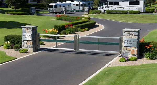 Premium RV resort entrance with dual-lane barrier gates and landscaped entry plaza