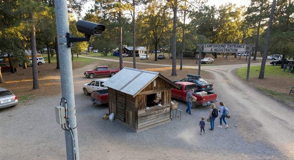 Security camera mounted on a pole overlooking a campground entrance and registration area