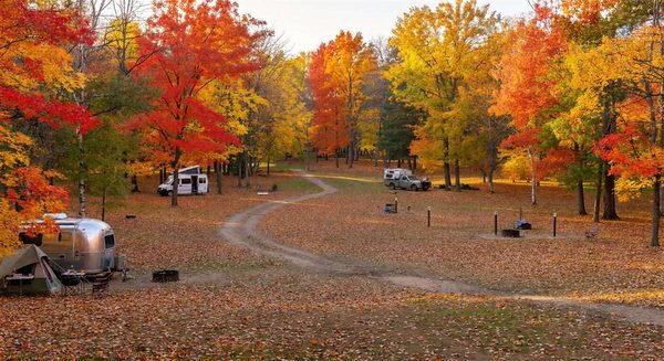 Beautiful autumn campground with colorful foliage and a few campers in a mostly empty park