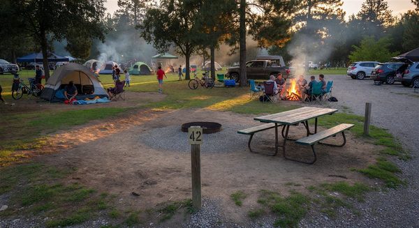 Empty reserved campsite on a busy weekend evening with other campers visible nearby